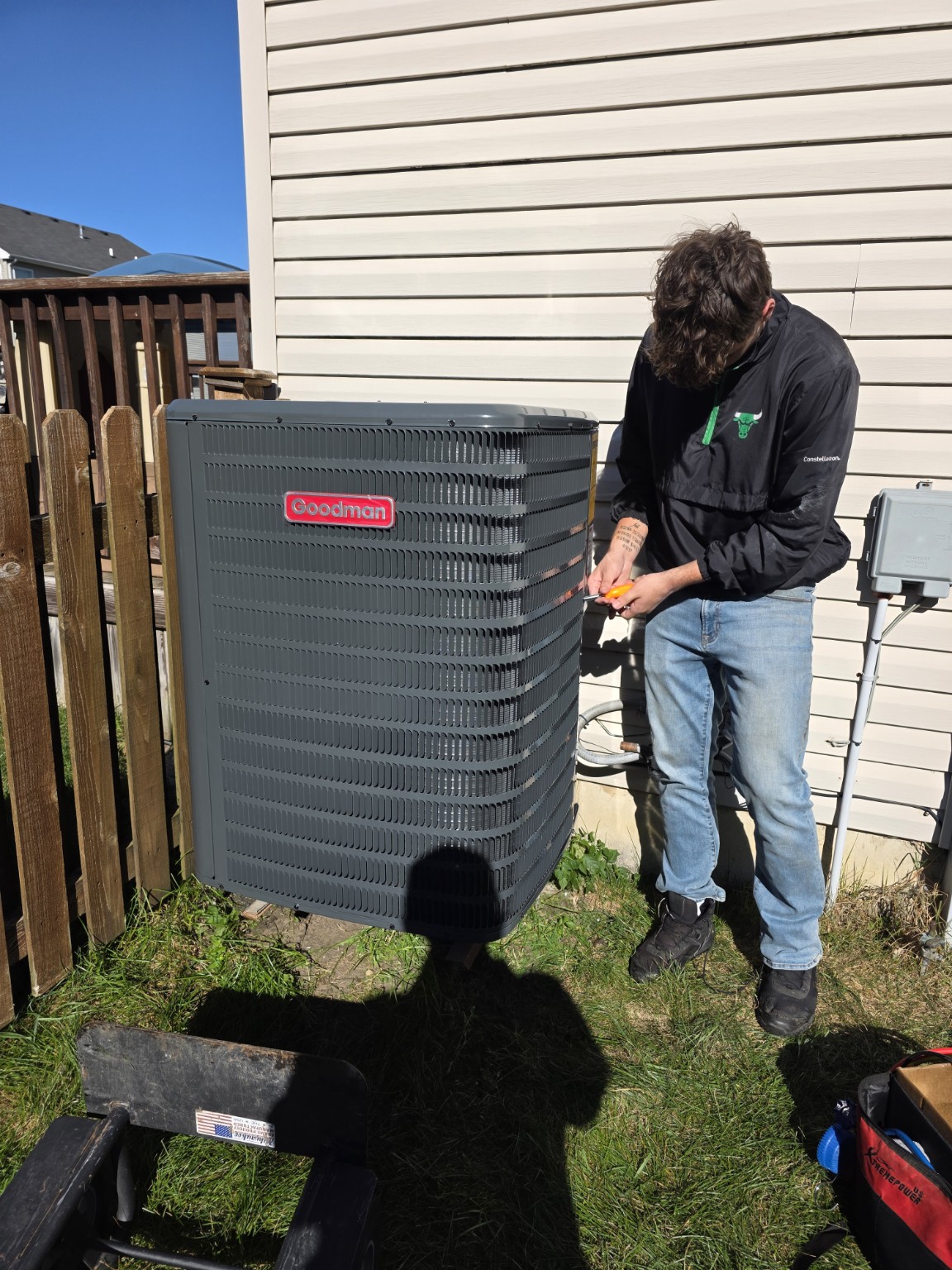 SteadyAir technician servicing an outdoor Goodman air conditioning condenser